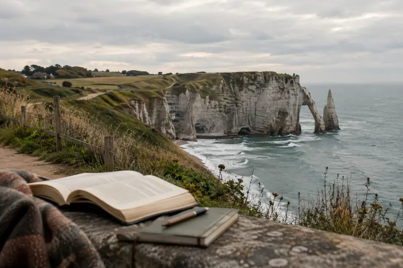 Un livre ouvert face aux falaises blanches et à l’Aiguille d’Étretat