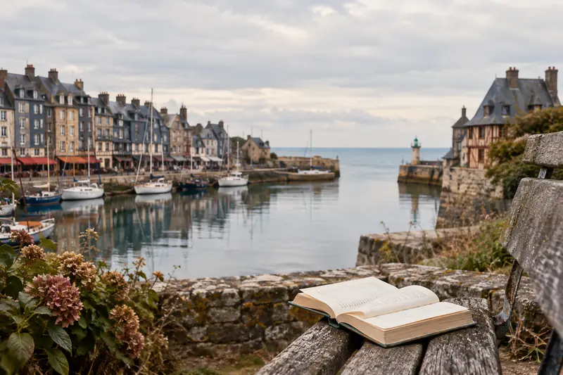 Livre ouvert face au port normand, entre les façades de Honfleur et la lumière de la mer